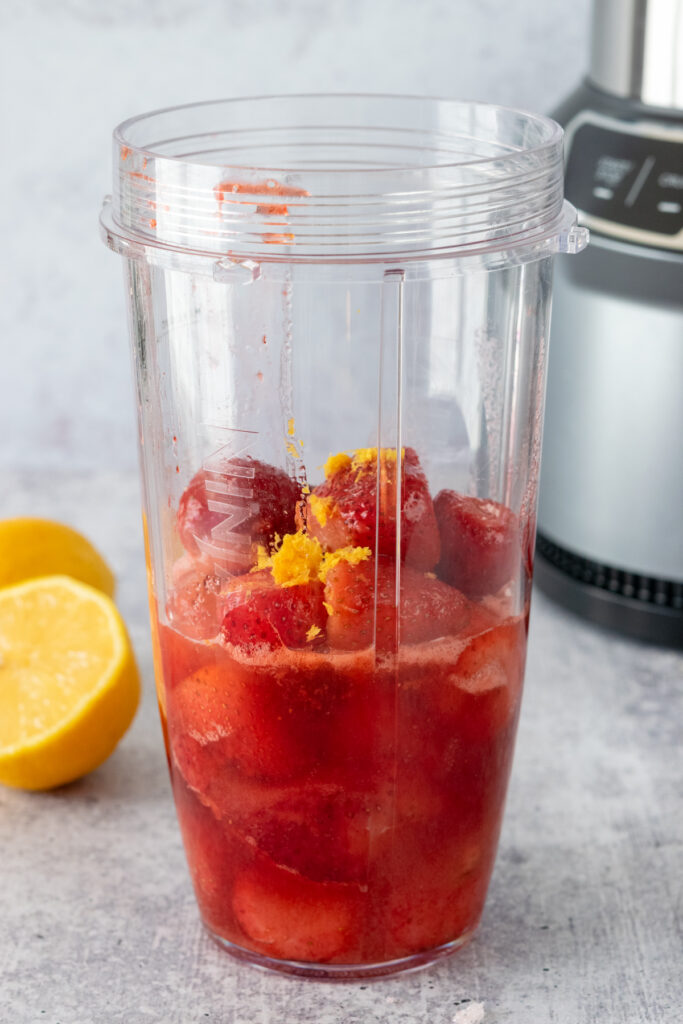 Lemon juice and lemon zest added to strawberry mixture in a blender.