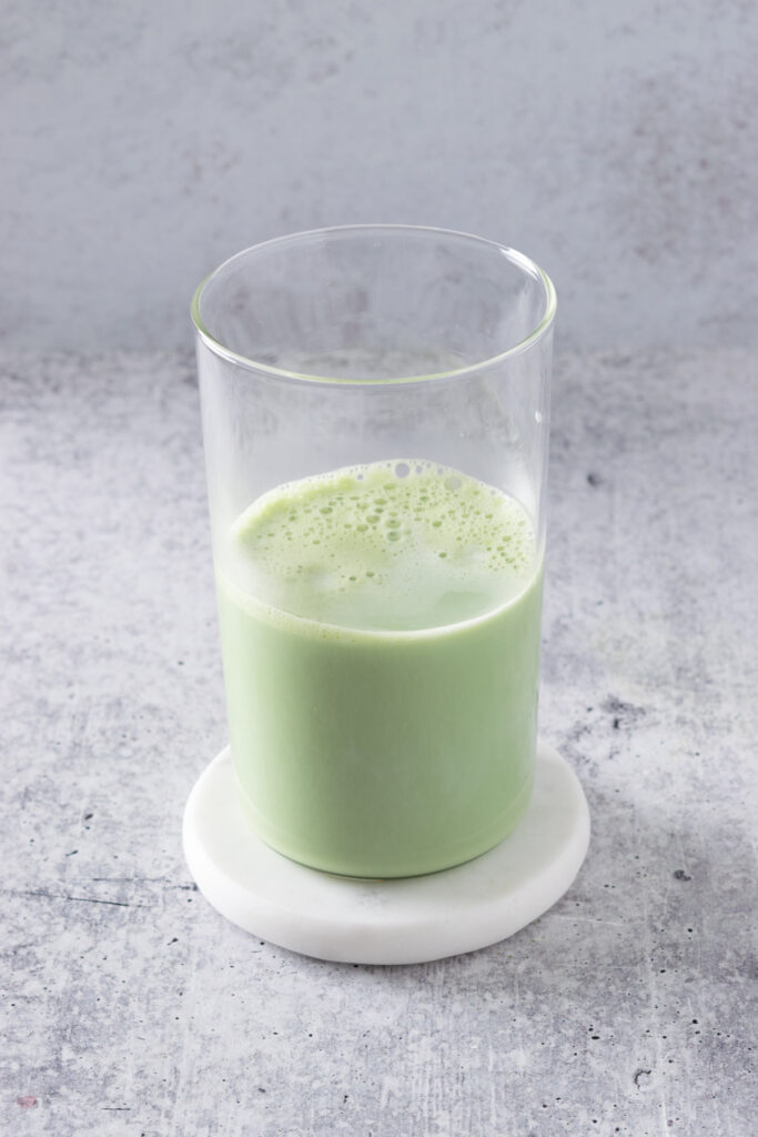 Milk added to glass of matcha green tea.