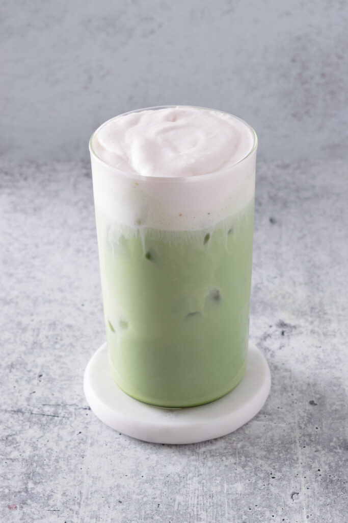 An iced strawberry cream matcha latte showing a pink and creamy top layer and a matcha green bottom layer.