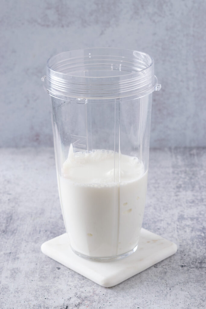 Milk added to blender cup with Greek yogurt.