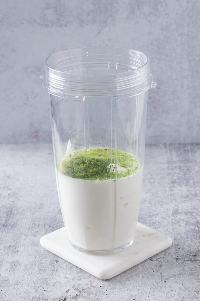 Matcha added to blender cup with milk and Greek yogurt.