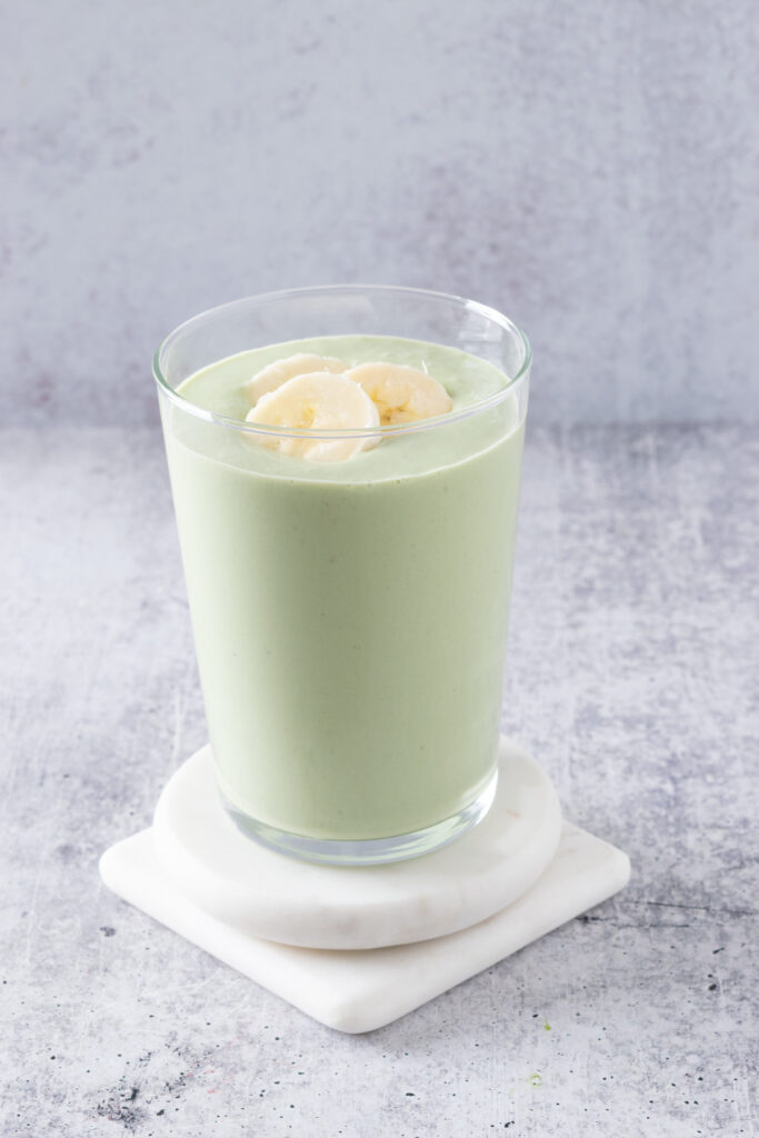 Matcha smoothie garnished with slices of fresh banana.