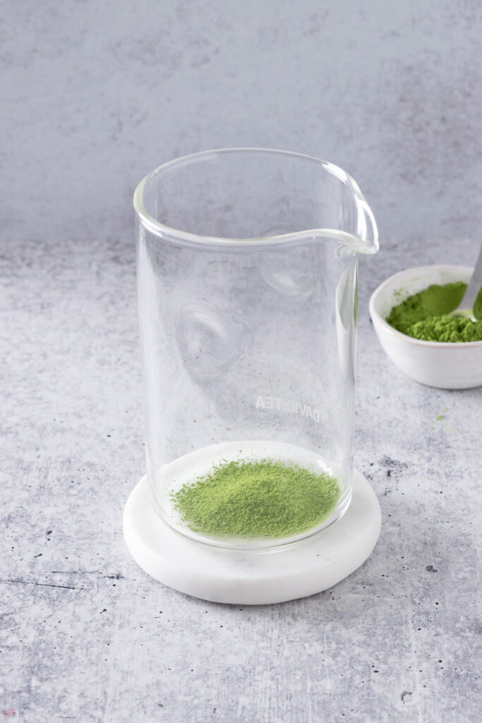 Sifted matcha green tea powder in a tall glass with spout.