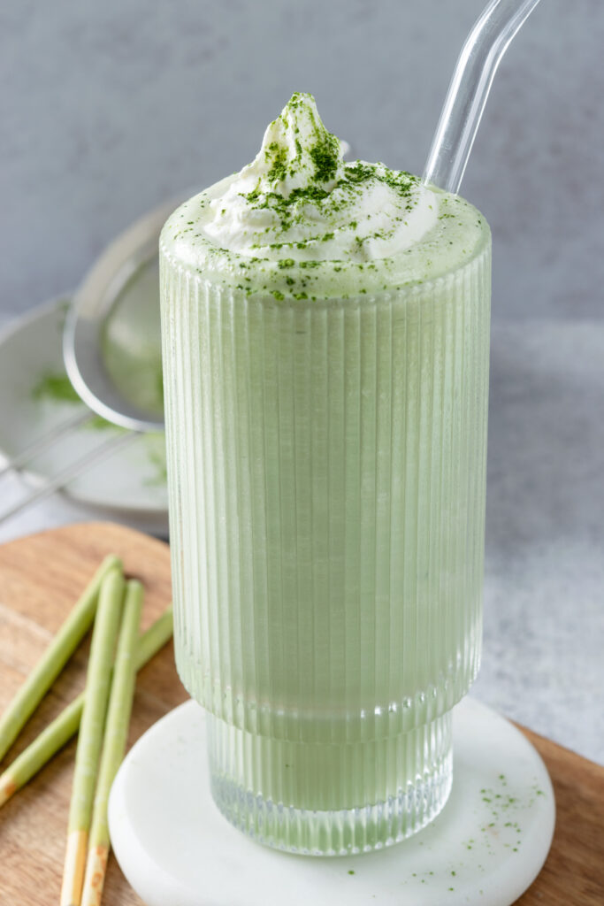 Homemade matcha milkshake with matcha flavored Pocky sticks on the side.