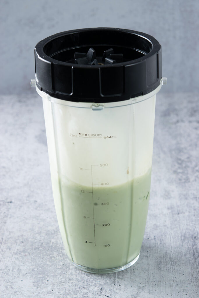 The blended matcha milkshake in the blender cup.