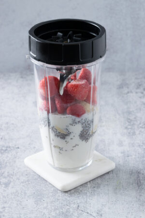 Smoothie ingredients in a Ninja compact blender cup.