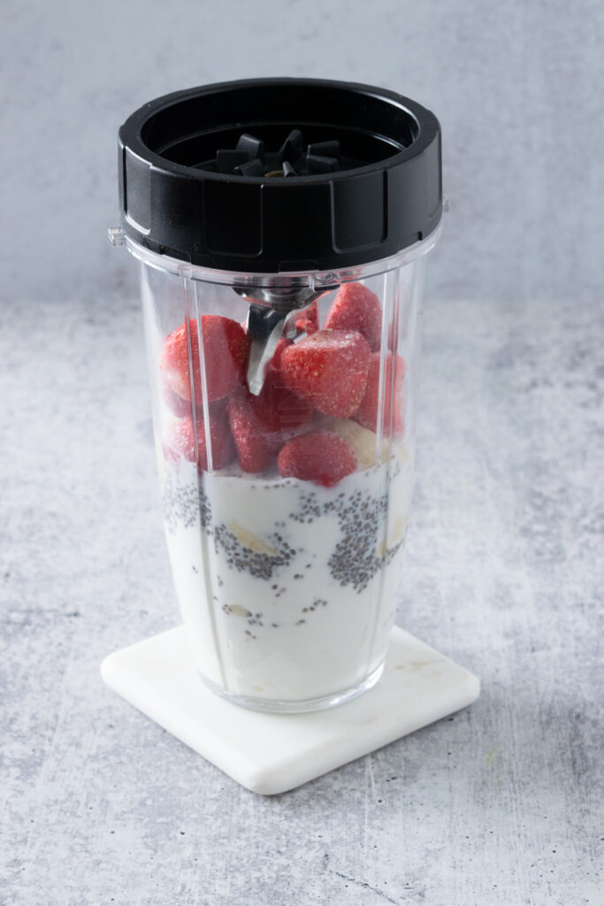 A single serve blender cup with the blade screwed on, ready to blend a strawberry banana chia seed smoothie.