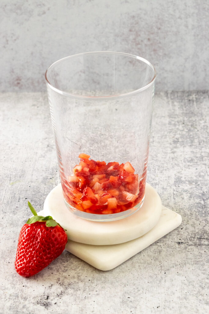 Macerated strawberries added to bottom of glass to make a matcha strawberry latte.