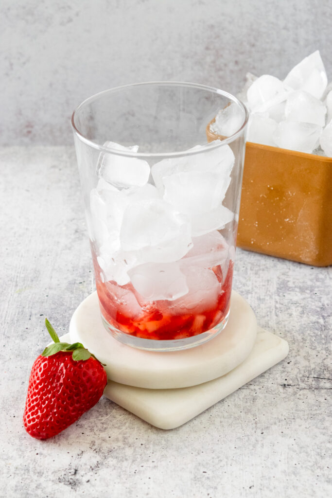 Ice cubes added to glass on top of strawberry layer.