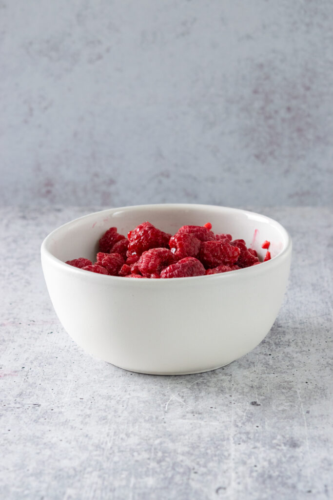 Bowl of frozen raspberries that has been thawed.
