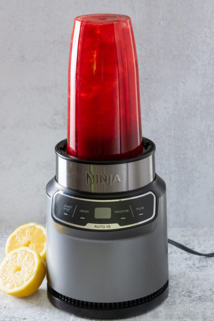Blender container on its base with the puree all blended.