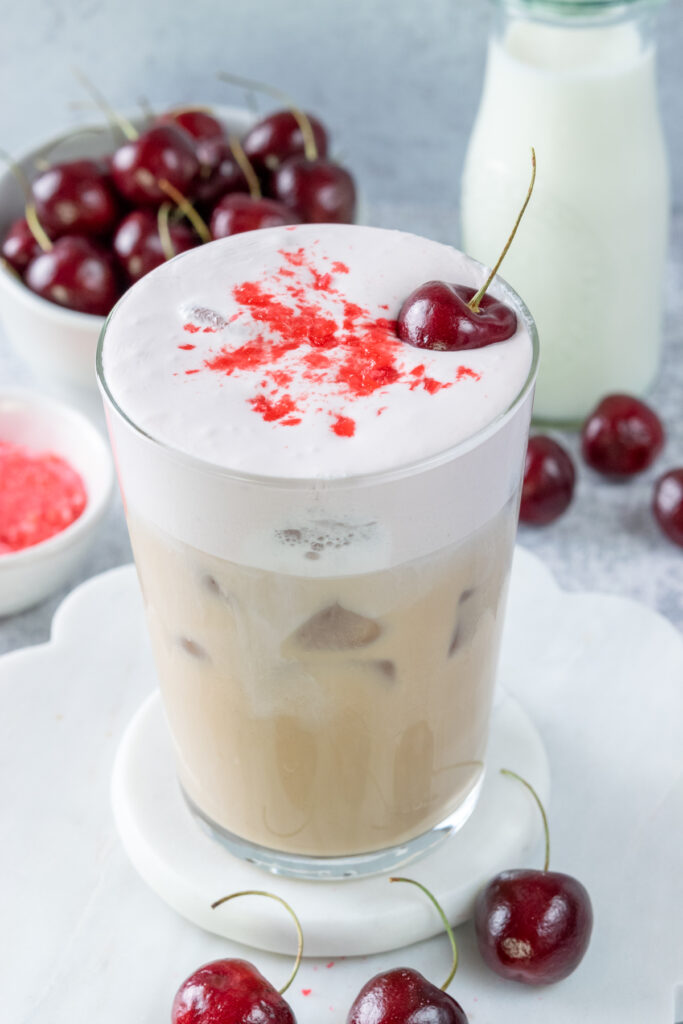 A top-down shot of an iced cherry chai showing the crushed cherry candy garnish on top of the layer of cherry cream.