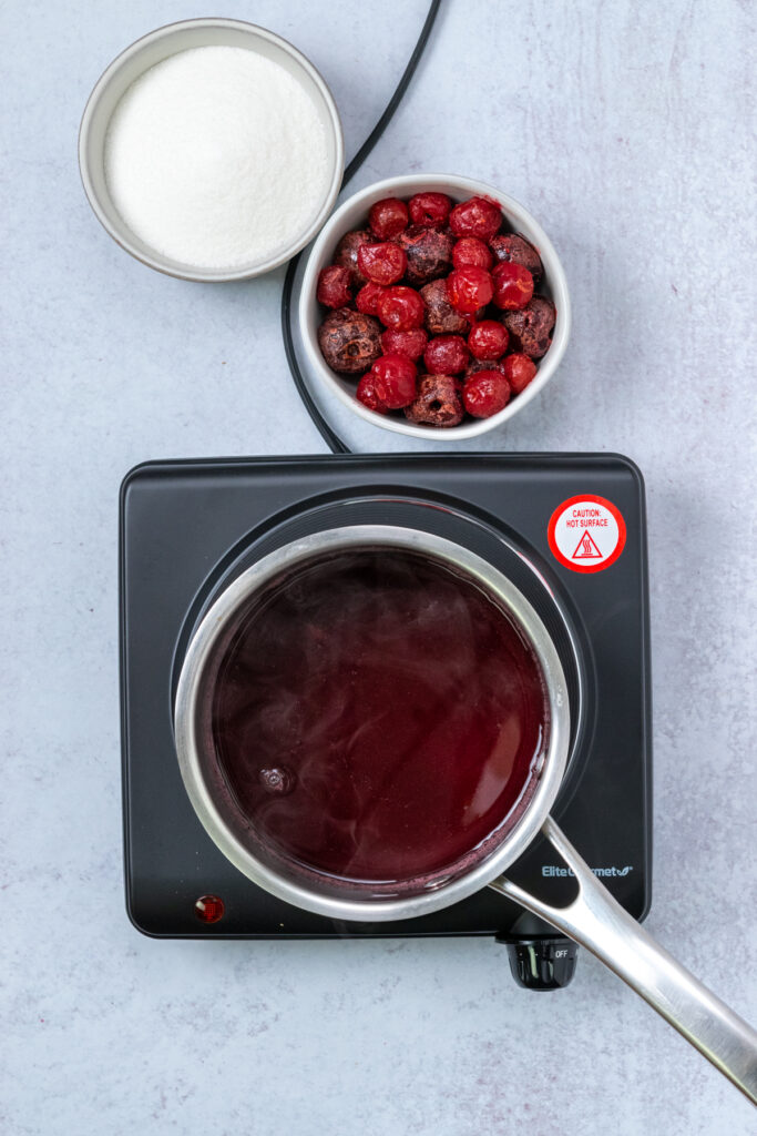 Sweetened cherry syrup in a saucepan on a burner to dissolve all the sugar.
