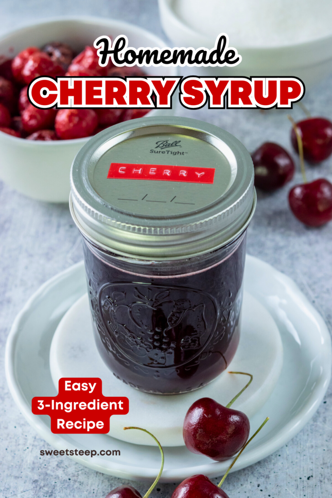 Homemade cherry syrup in a small mason jar with a label on the lid that says, "cherry." The jar of syrup is next to a bowl of cherries and a bowl of sugar.