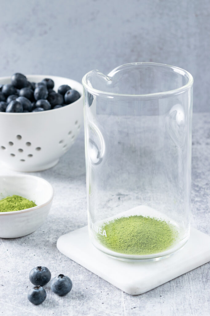 Glass measuring cup with sifted matcha powder ready to be whisked.