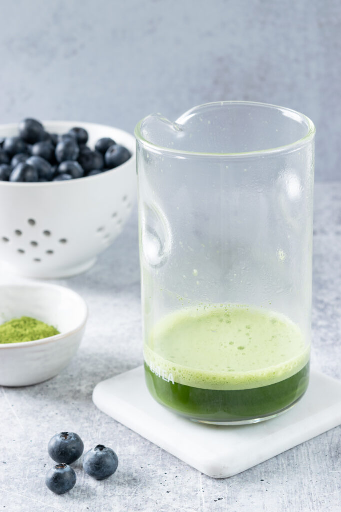 Hot water added to matcha powder and whisked in a glass measuring cup until frothy.