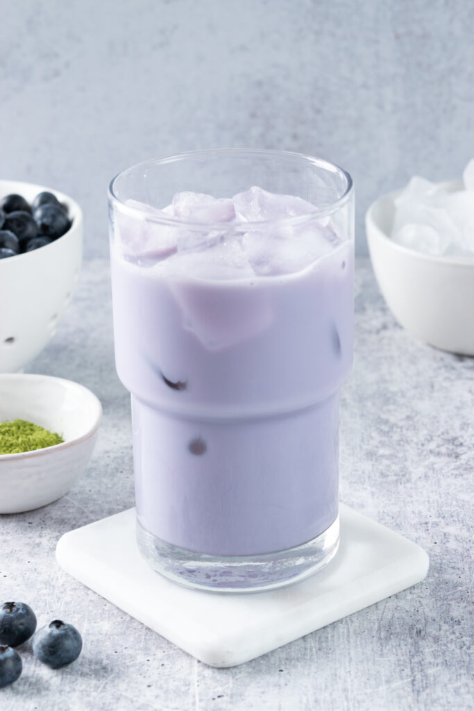Ice cubes added to the blueberry milk mixture, preparing for the matcha layer.