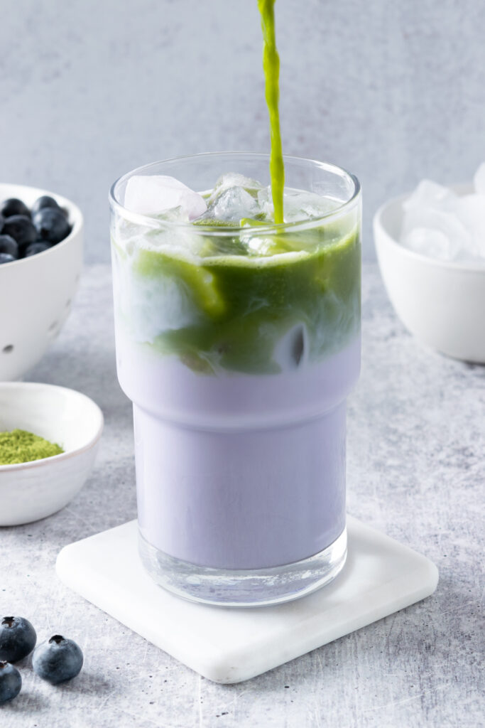 Whisked matcha being poured over ice for the final layer of the blueberry matcha latte.