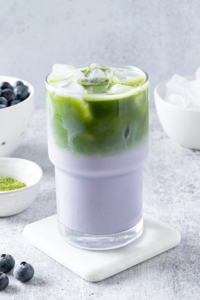 Completed iced blueberry matcha latte showing vibrant green and purple layers in a clear glass.