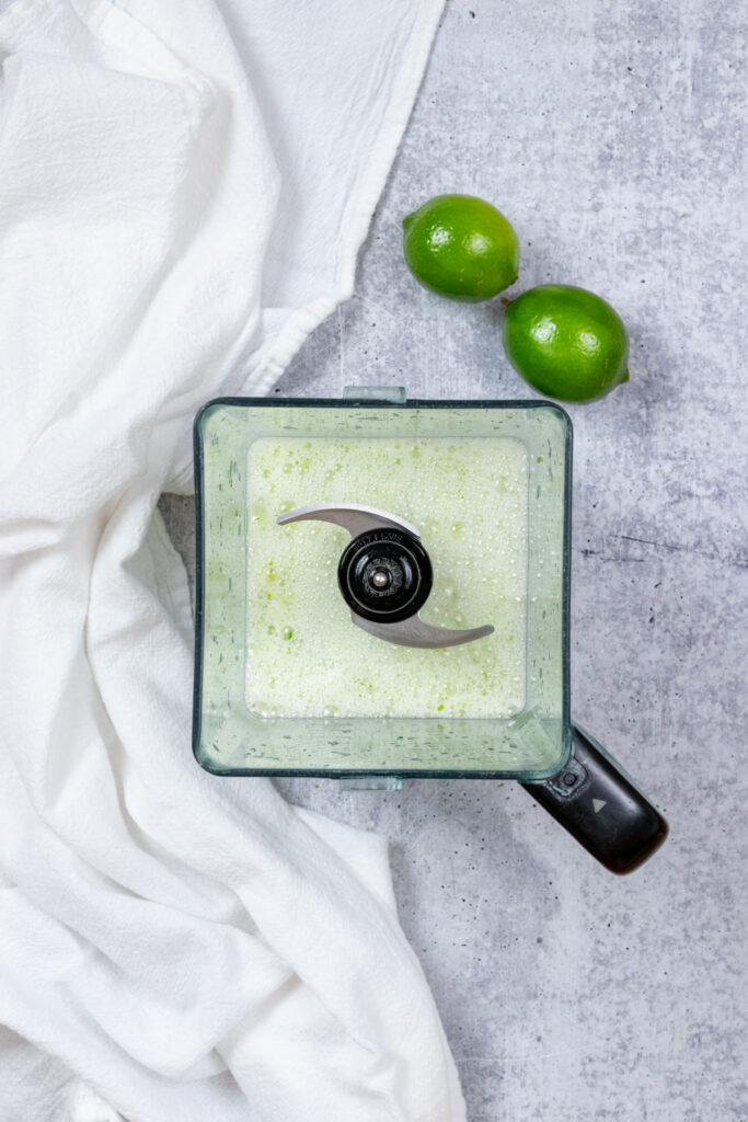 Overhead view showing frothy lime juice in a blender after blending.