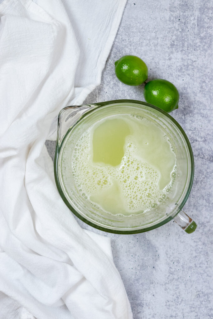 A bowl of the blended lime water with bubbles on top. All the solids have been strained out.