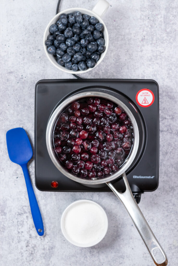 Blueberries and water in a saucepan on the stove.