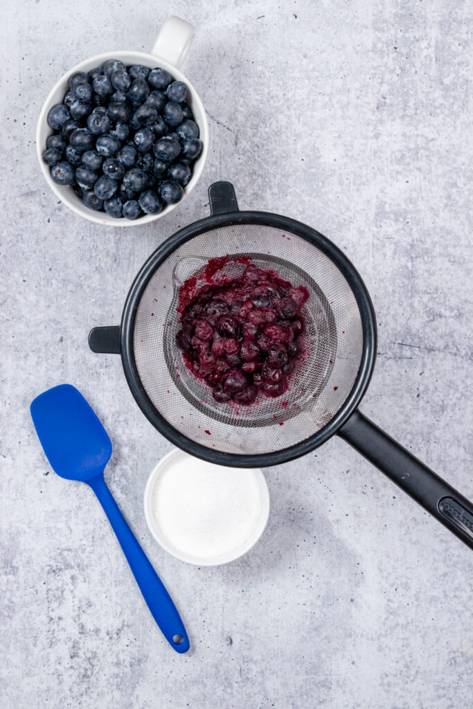 A strainer full of blueberry pulp.