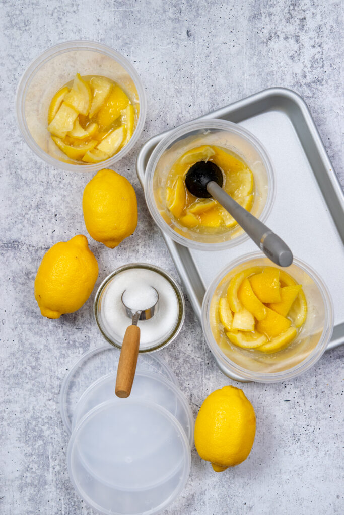 An overhead photo of smashed homemade lemonade being made directly in the cups. The center cup has a muddler in it and you can see how the lemons have released their juice and the sugar has dissolved.