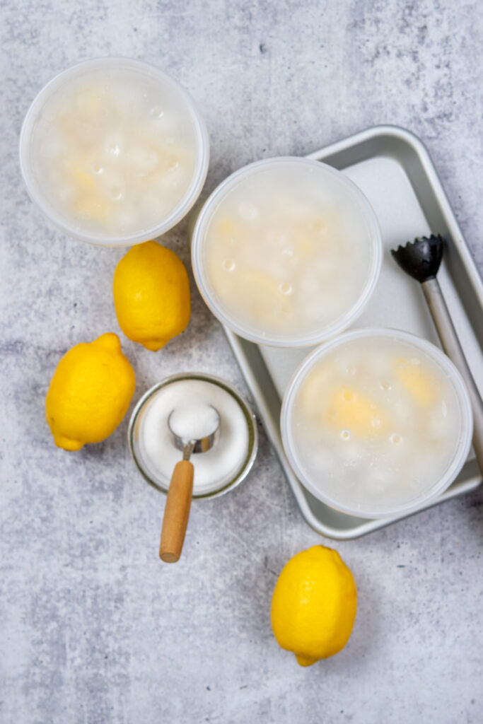 The deli container lids are placed on the three homemade lemonades and shaken to combine.