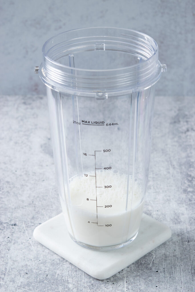 Milk added to blender cup to make a peach smoothie.