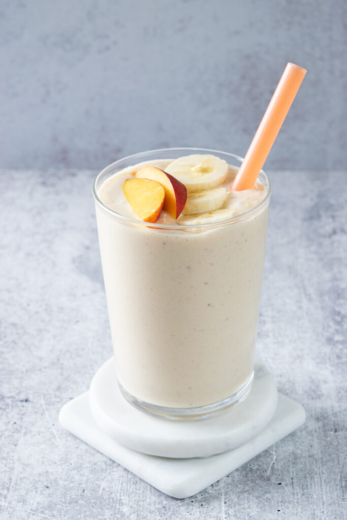 The smoothie is garnished with slices of banana and peach.