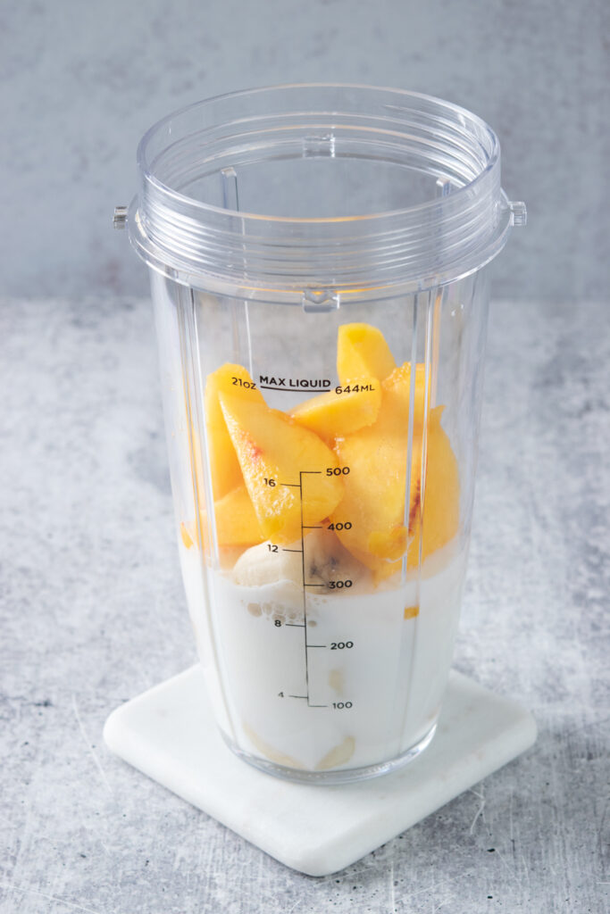 Sliced fresh peaches and frozen banana added to blender cup with the milk.