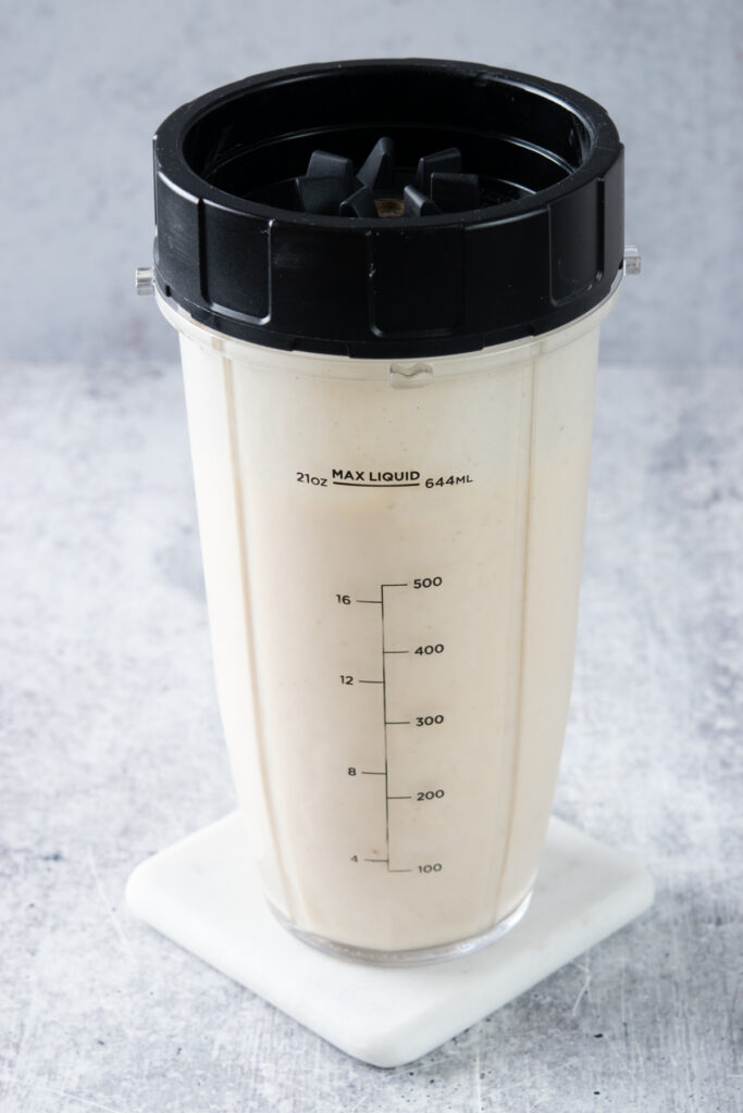 A blended peach banana smoothie still in the blender cup with the lid on.