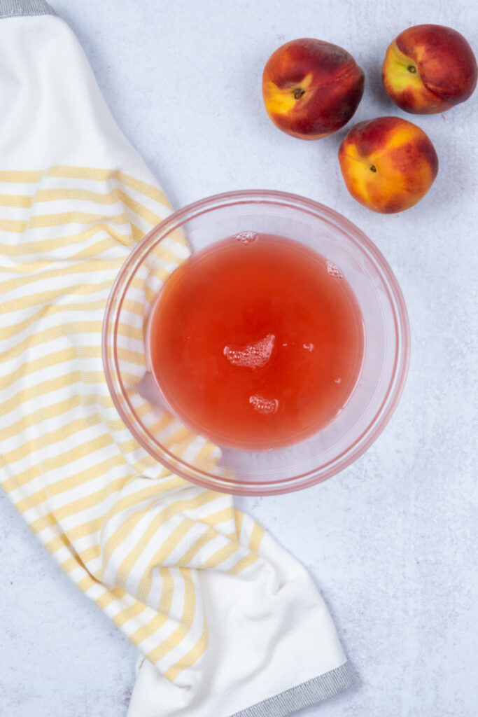 Pinkish peach juice collected in the bowl after straining and pressing.