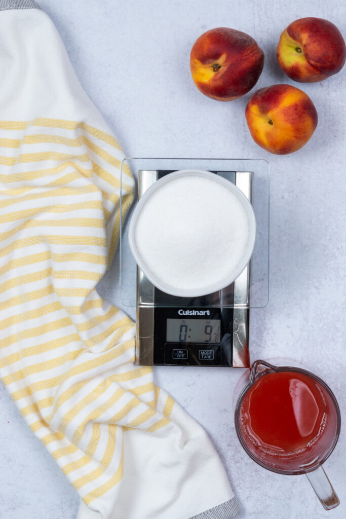 Sugar being weighed on the kitchen scale to match the weight of the peach juice.