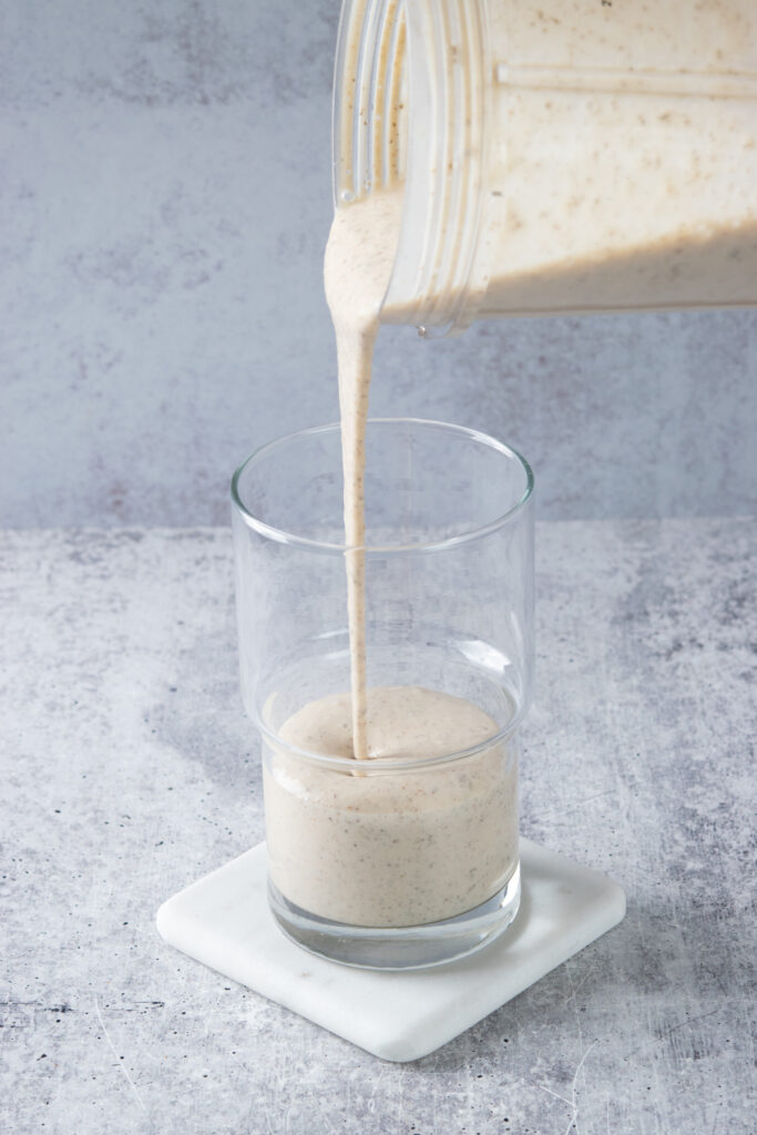 Pouring the smoothie into a drinking glass.