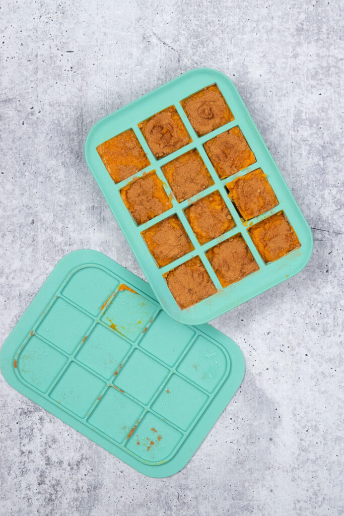 An ice cube tray filled with pumpkin puree that's sprinkled with pumpkin pie spice, to make a pumpkin smoothie freezer pack.