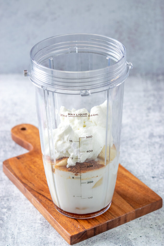 Vanilla, salt, maple syrup and Greek yogurt added to a blender cup that already has the milk, banana and spice.