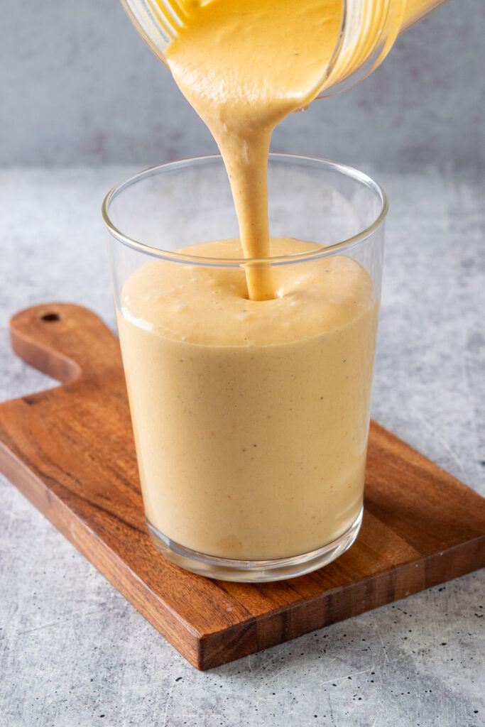 Pouring the pumpkin smoothie into a drinking glass.