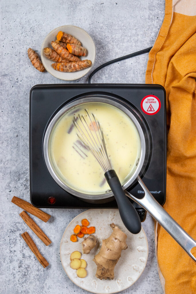 Whisking the turmeric latte in a saucepan. It's turned a golden color from the turmeric root.