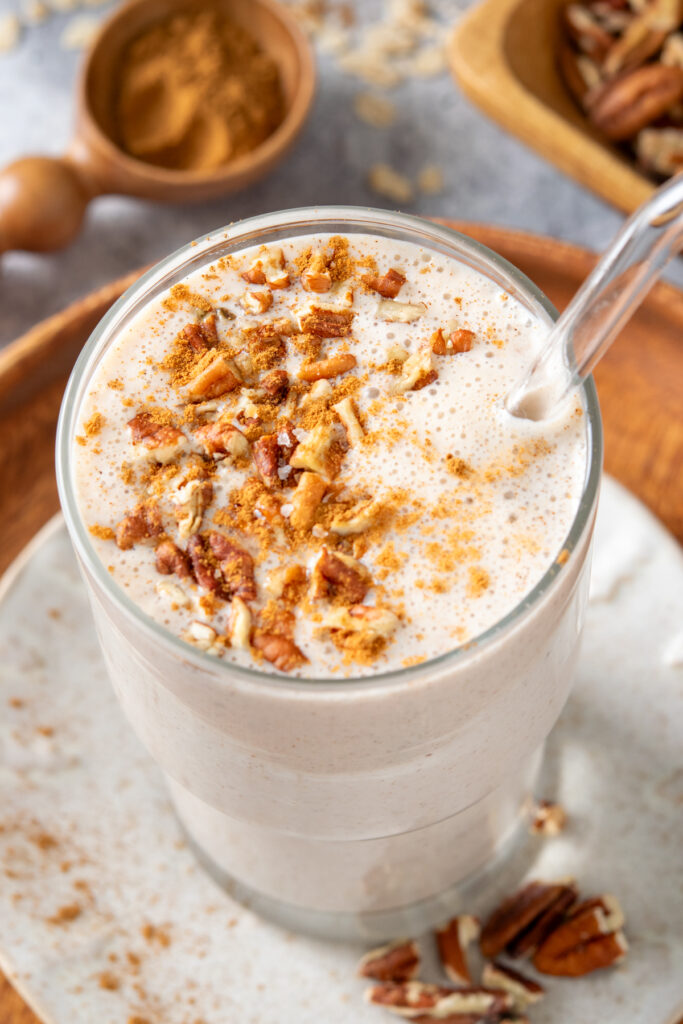 A creamy pecan oatmeal smoothie that has chopped pecans and cinnamon sprinkled on top and looks really tempting to drink.