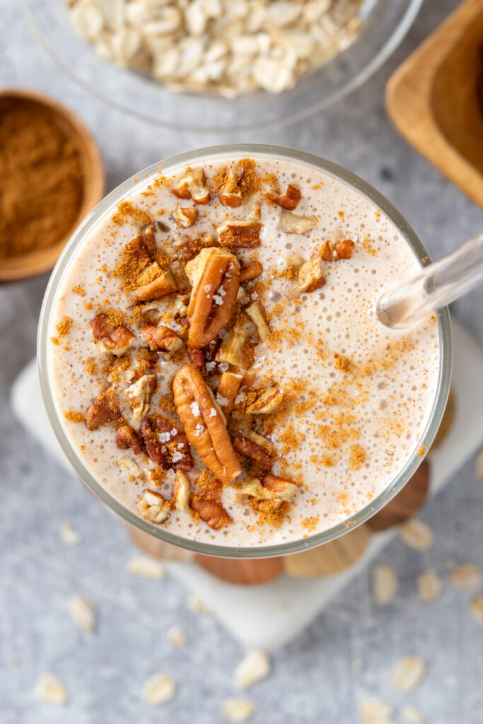 The top of a thick and creamy oatmeal smoothie that has crunchy chopped pecans on top and is sprinkled with ground cinnamon.