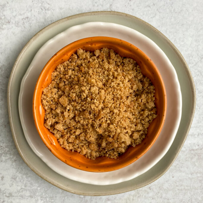 An orange bowl with pie crust crumbles for to use as a latte drink topping.