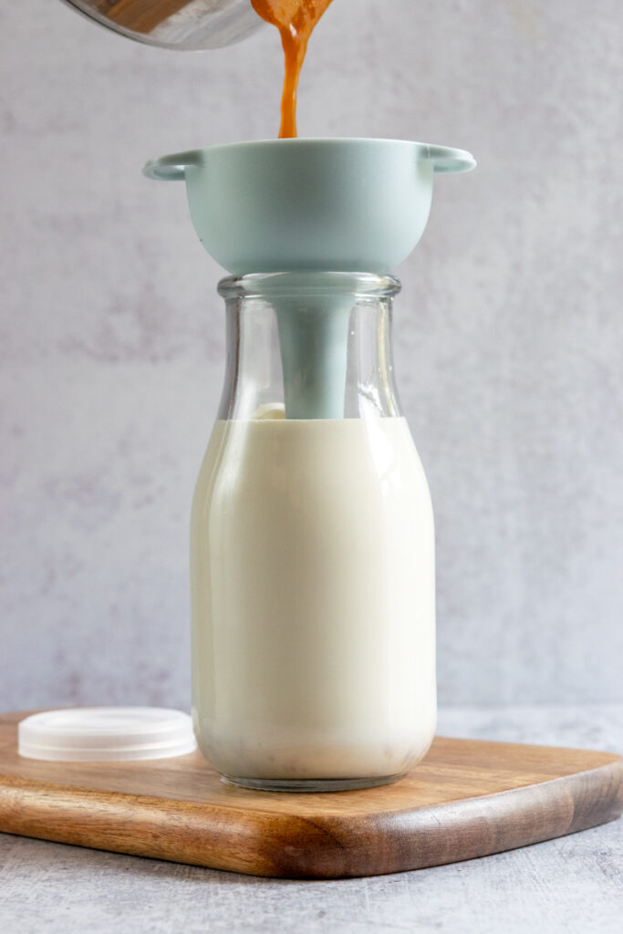 Adding pumpkin spice syrup to bottle of cream and milk.