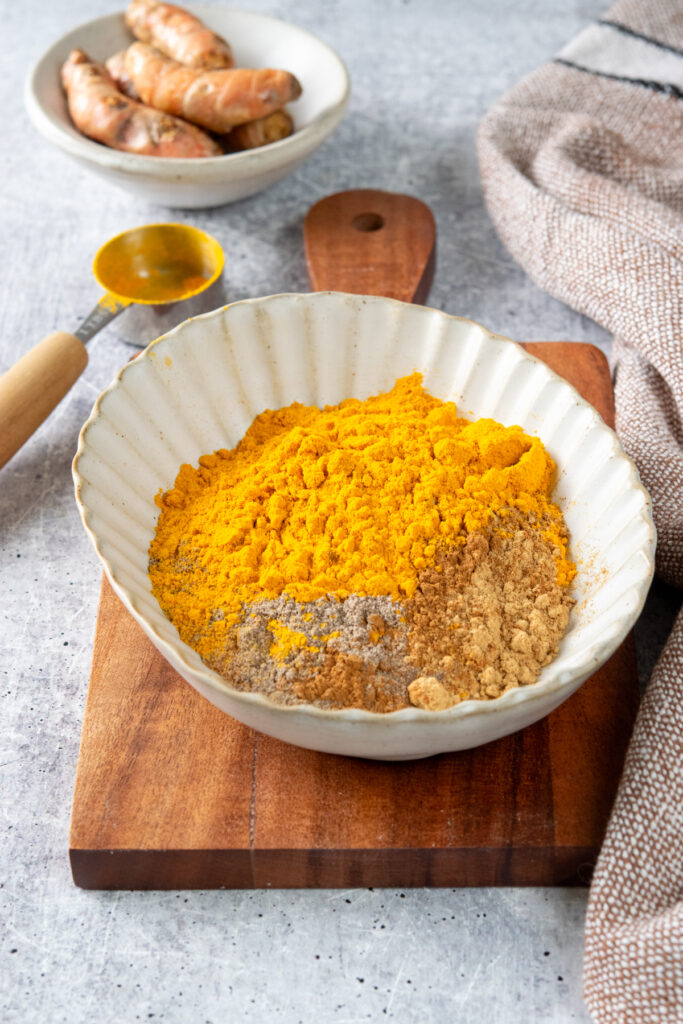 Spices to make turmeric latte mix in a bowl before being stirred together.