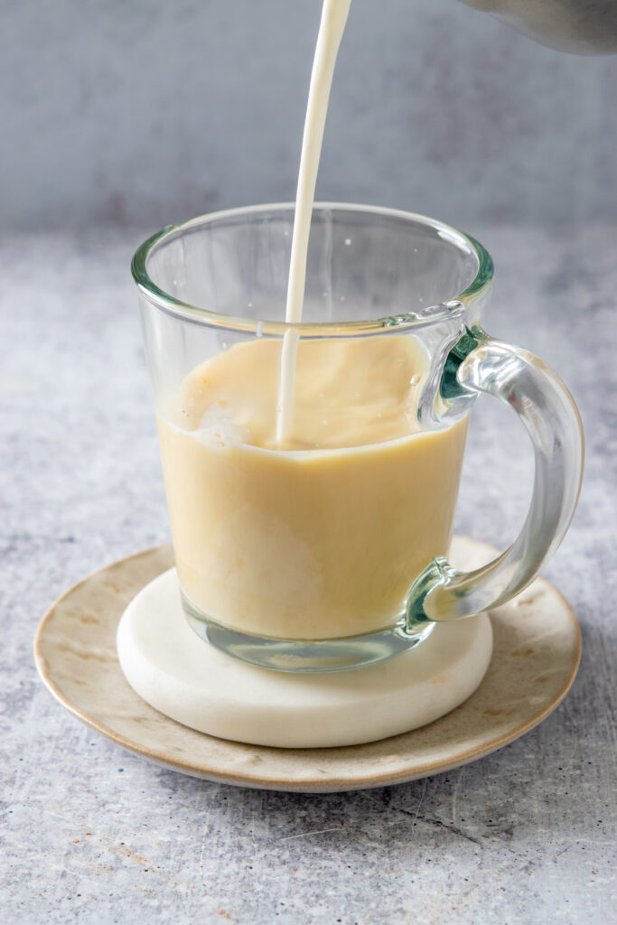 Continuing to pour the steamed milk to make a turmeric latte. You can see that the drink is golden in color.