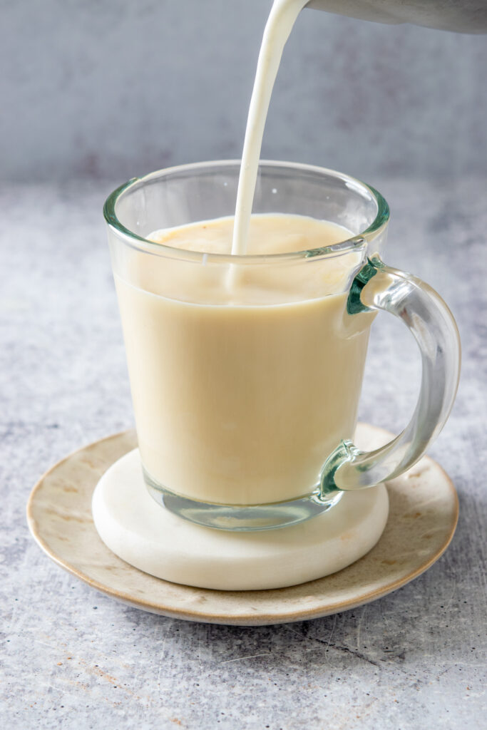 Topping off the hot turmeric latte with steamed milk.