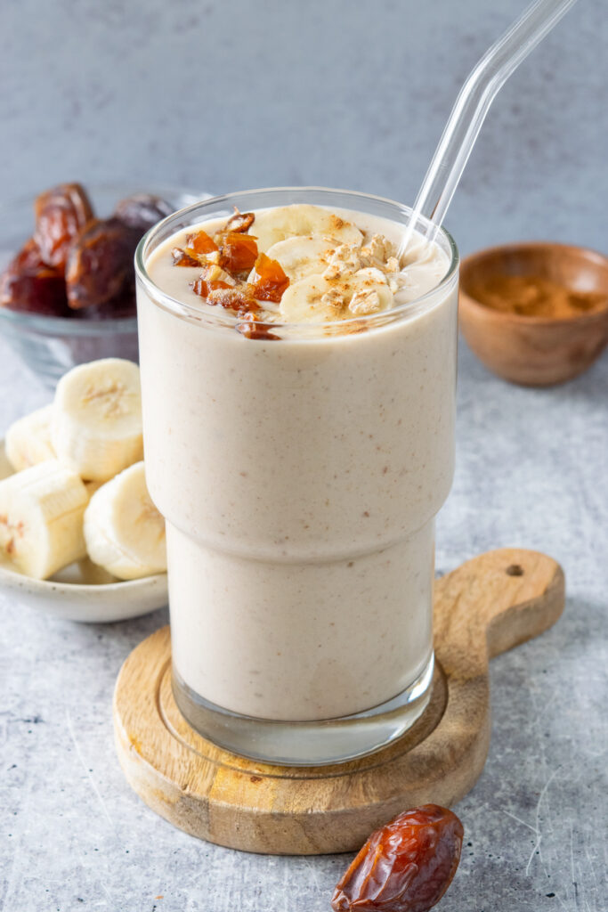 A homemade banana date smoothie. You can see flecks of chopped dates in the thick and creamy breakfast smoothie, which is garnished with even more dates and bananas.