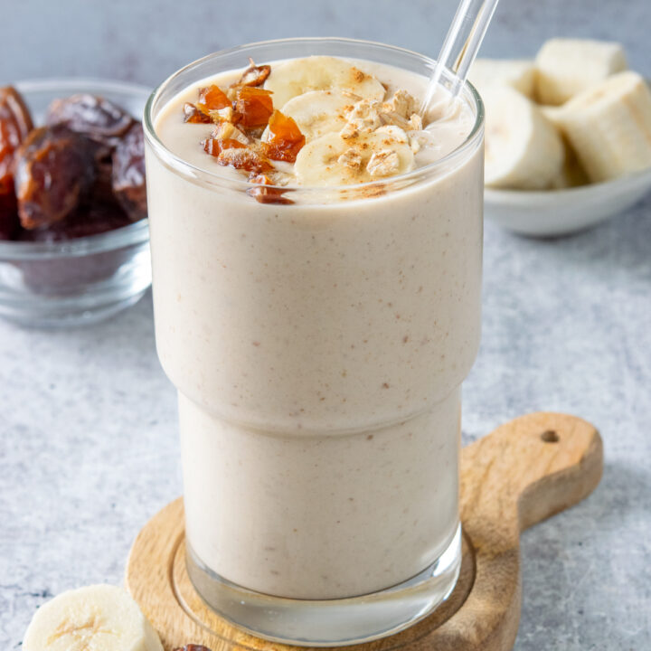 Homemade banana data smoothie garnished with chopped medjool dates, banana slices, oats and cinnamon.
