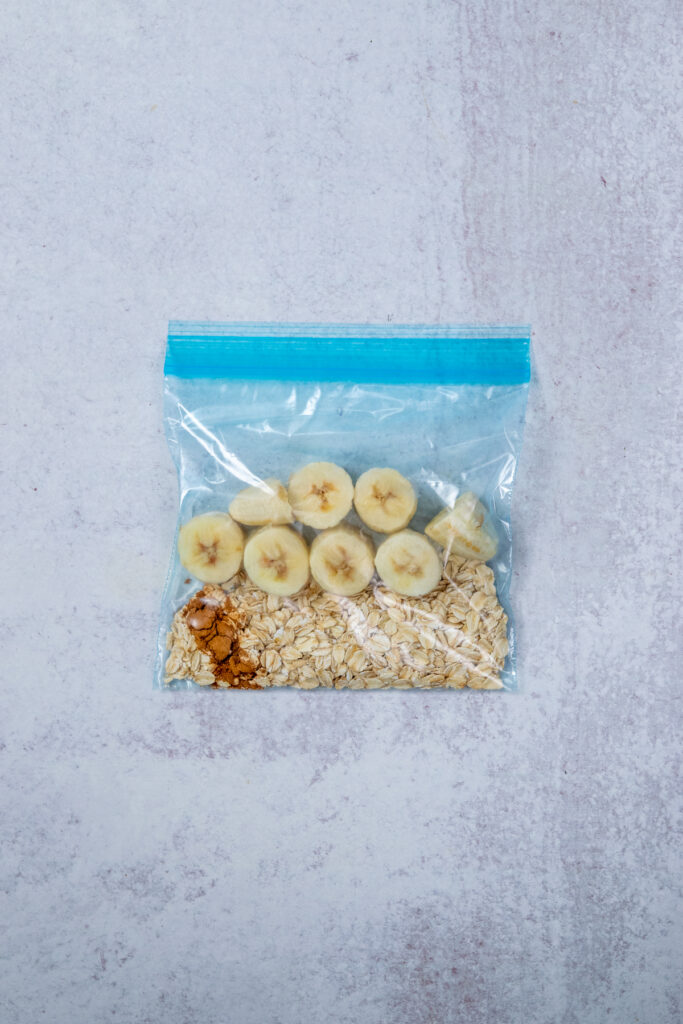A smoothie freezer pack that contains measured oats, cinnamon, salt and frozen banana chunks to make a banana date smoothie.